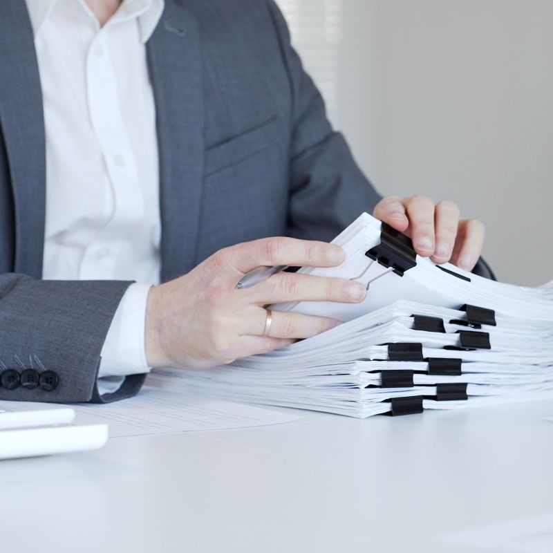 Business professional sorting through a large stack of clipped compliance documents.